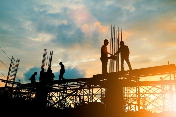 Silhouette of engineer and construction team working at site over blurred background sunset