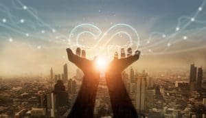 Hands holding a circular economy icon in front of a cityscape