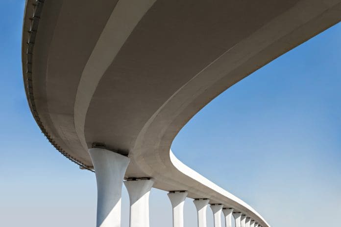 Roadway in the sky A curved concrete bridge against a blue sky