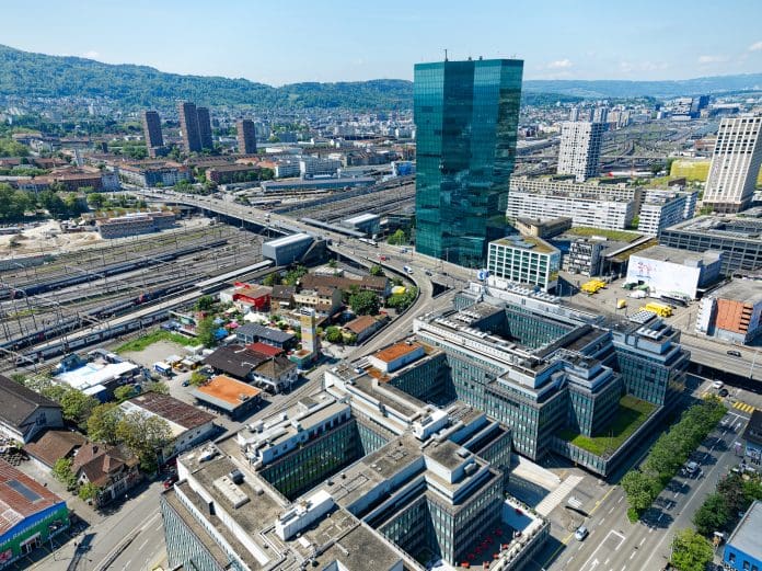 Drone point of view over Swiss town with skyscraper and highway bridge with Limmat valley in the background. Aerial shot of Zurich, Switzerland, which has been ranked first in the 2025 Smart City Index