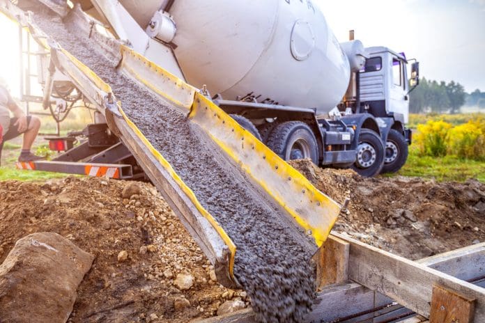 Pouring concrete to the foundations of the building Pouring concrete to the foundations of the building. Construction Worker Guiding Cement Mixer Truck Trough. Cement Pouring from a Mixer Truck Chute. Concrete Foundation Construction.